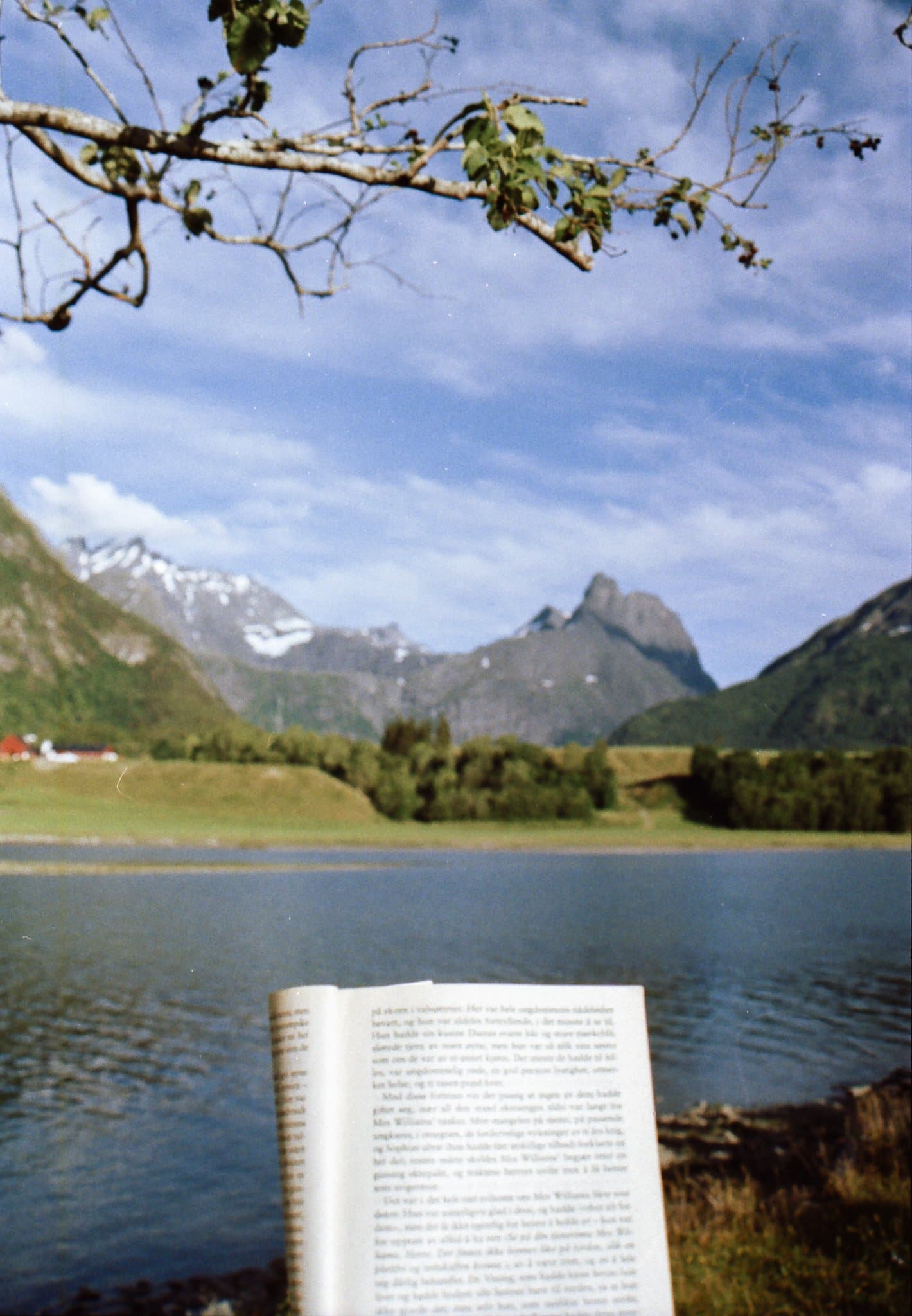Oppslått bok foran fjell og vann i norsk natur
